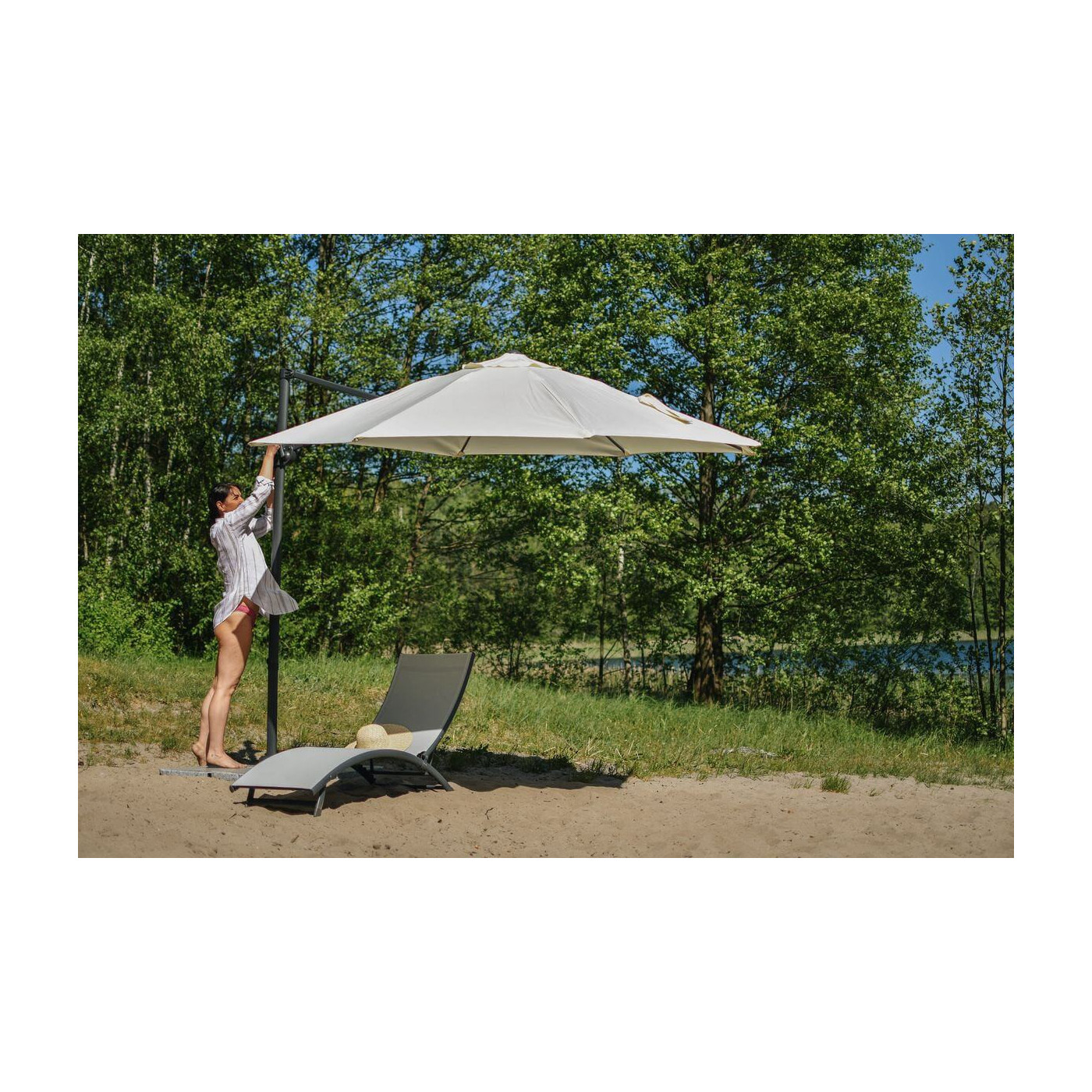 Kobieta rozkładająca parasol ogrodowy nad leżakiem star light grey