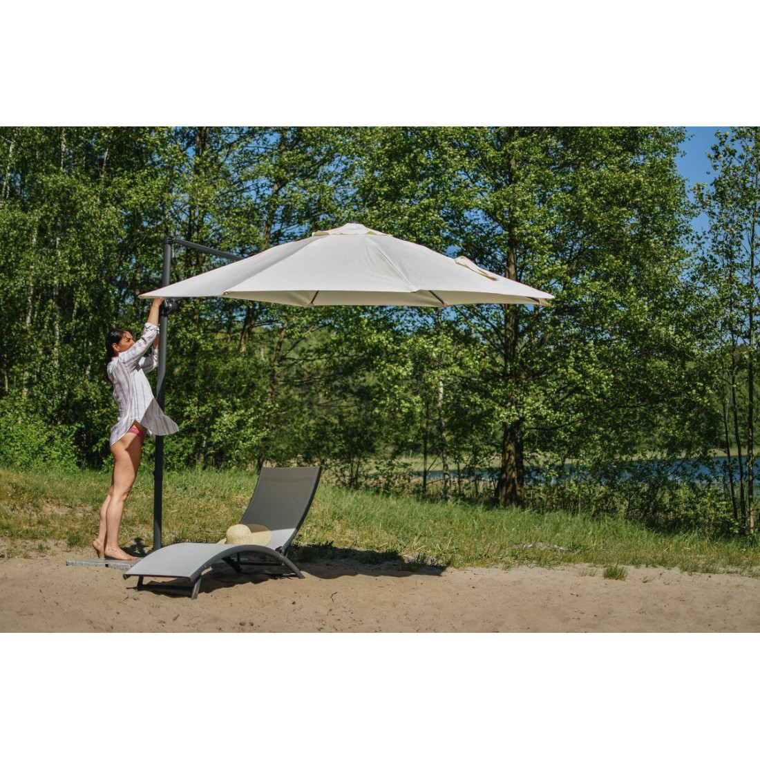 Kobieta rozkładająca parasol ogrodowy nad leżakiem star light grey