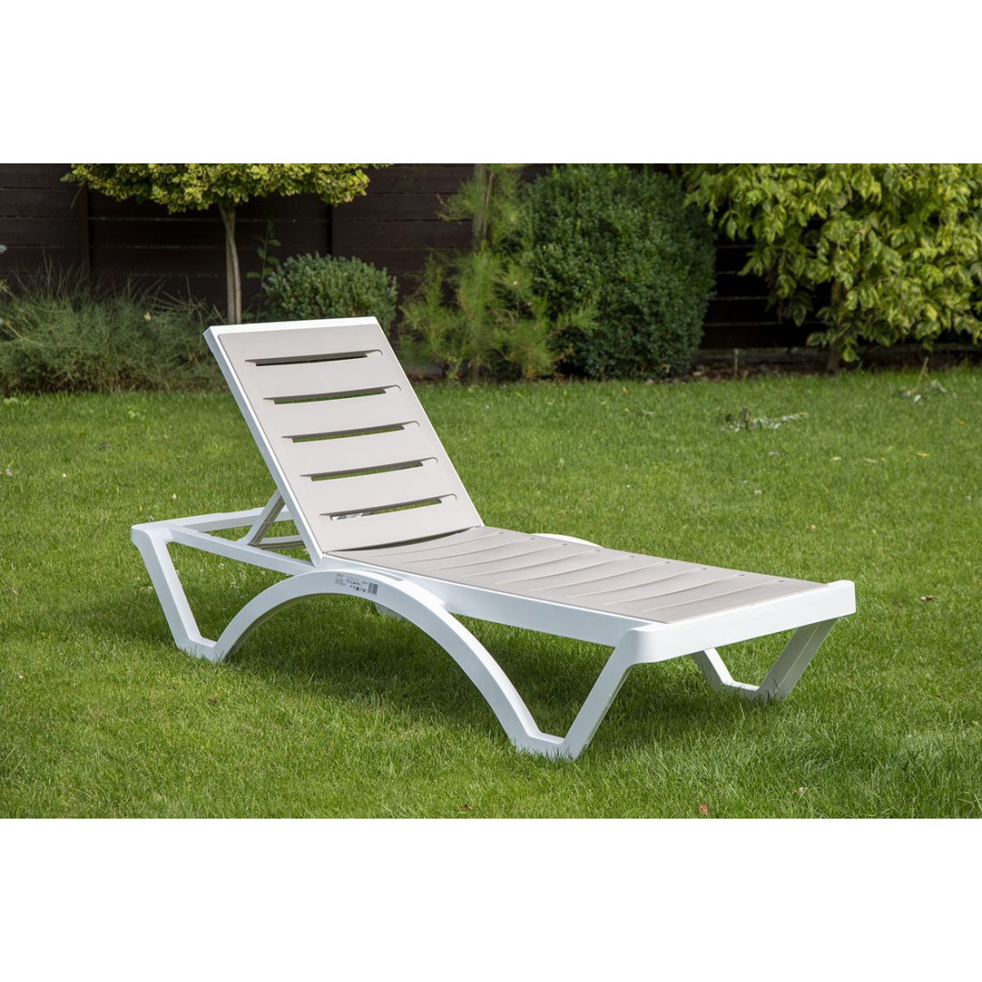 leżak lombok z białą ramą i szarobrązowym oparciem na ogrodzie